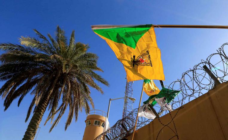 A member of Hashd al-Shaabi (paramilitary forces) holds a flag of Kataib Hezbollah militia group in Baghdad.