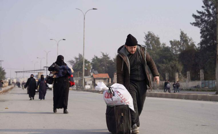 People walk with their belongings along a road, after Syrian government forces and the Kurdish-led Syrian Democratic Forces agreed to de-escalate in Aleppo, December 23, 2025. 
