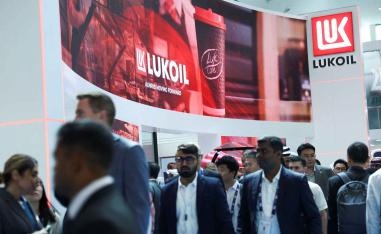 People walk past the booth of Lukoil during the annual energy industry event Abu Dhabi International Petroleum Exhibition and Conference (ADIPEC) in Abu Dhabi, November 3, 2025. 