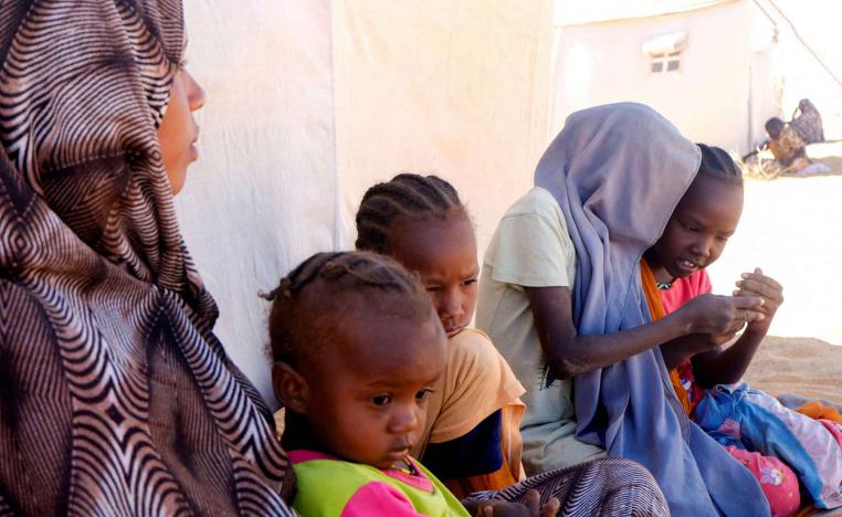 A displaced mother sits with her children in front of their tent, in a displacement camp in Al-Dabbah, Sudan, November 15, 2025. 