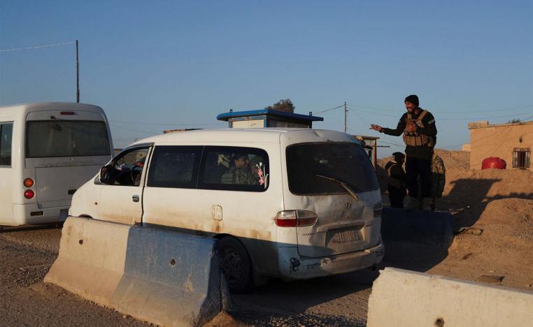 A member of the Syrian army interacts with other members of the Syrian army siting in a vehicle, which is headed to Al-Hasakah