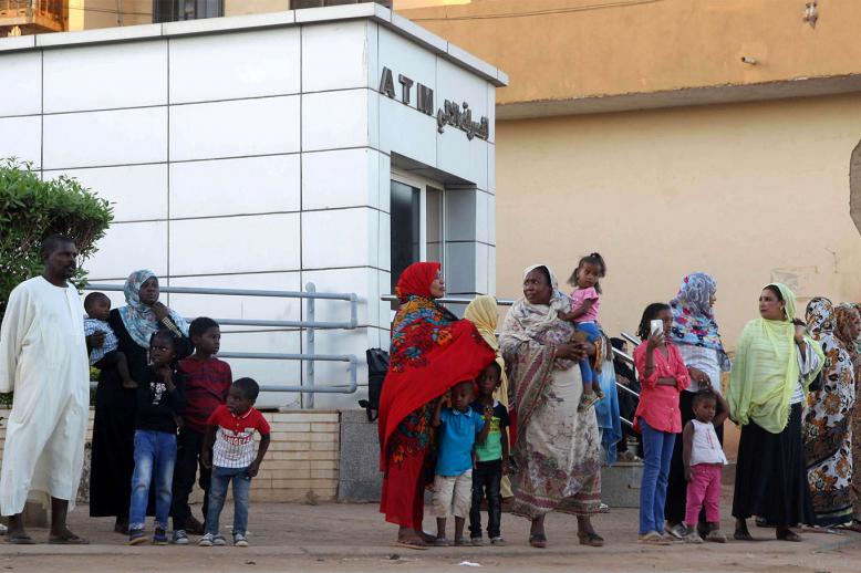 Residents stand outside an automated teller machine (ATM) in Khartoum