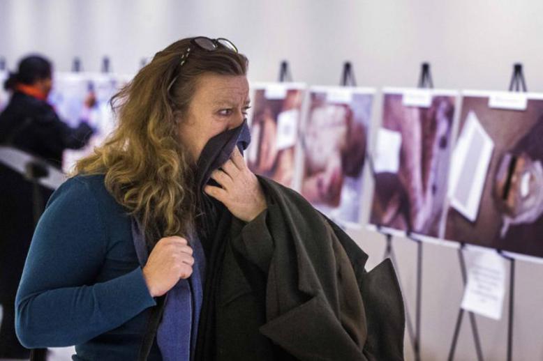 A woman reacts as she looks at a gruesome collection of images of dead bodies taken by a Syrian photographer, who has been identified by the code name "Caesar", at the United Nations Headquarters in New York.