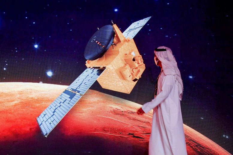 إماراتي يمر عبر شاشة تعرض مسبار "الأمل" في مركز محمد بن راشد للفضاء في دبي في 19 يوليو 2020 قبل إطلاقه من اليابان