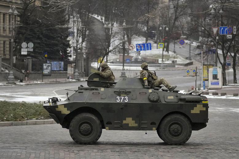 Ukrainian servicemen ride on top of an armored personnel carrier in Kyiv