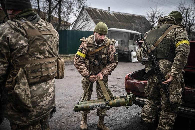 Ukrainian soldiers unload weapons from the trunk of an old car, northeast of Kyiv 
