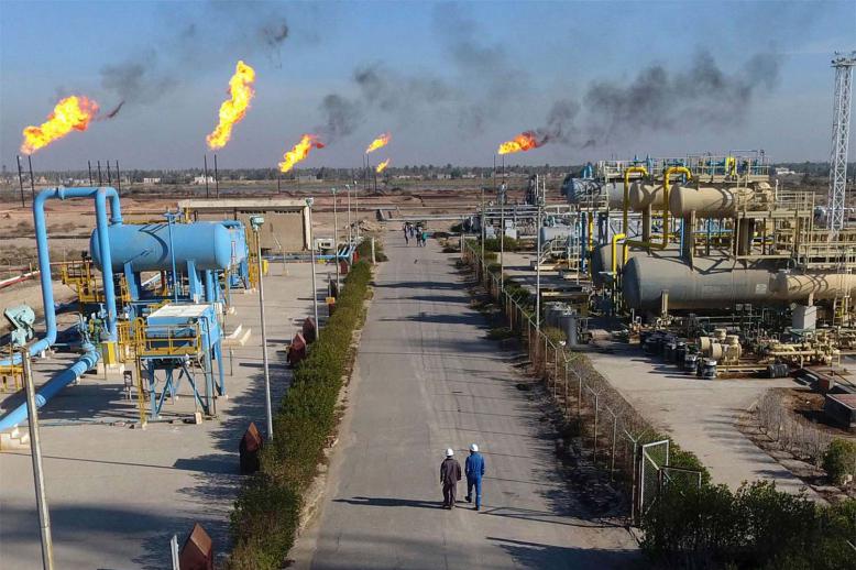 Labourers walk down a path in the Nihran Bin Omar field north of Basra