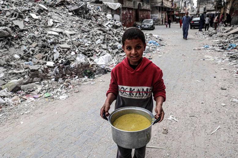 طفل فلسطيني مع قدر من المساعدات في رفح