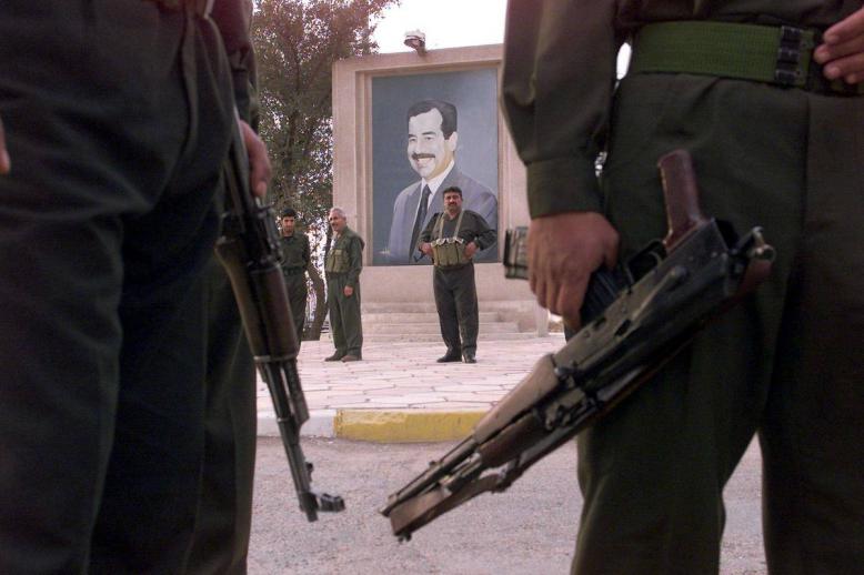 مسلحون عراقيون أمام صورة للرئيس العراقي صدام حسين في بغداد (مارس 2003)