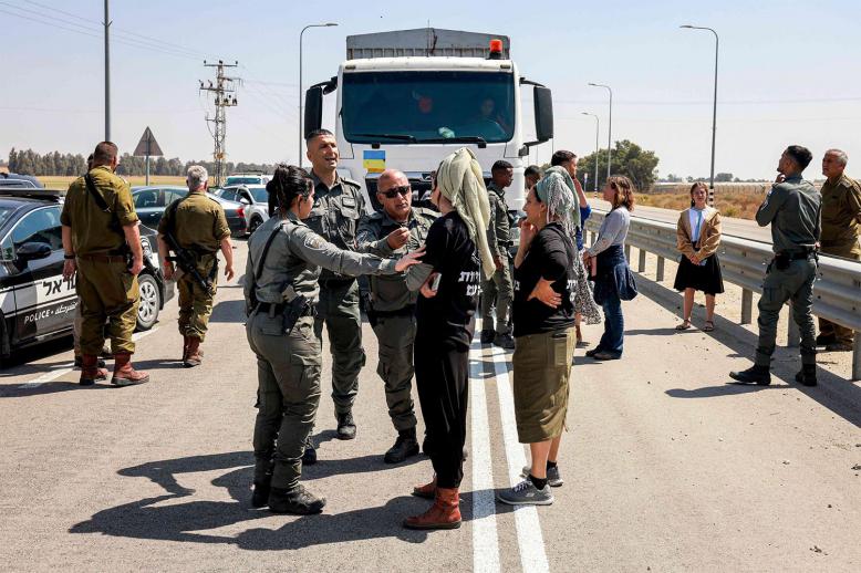 Israeli border guards talk to right-wing protesters blocking the road to Jordanian trucks carrying humanitarian aid supplies to Gaza