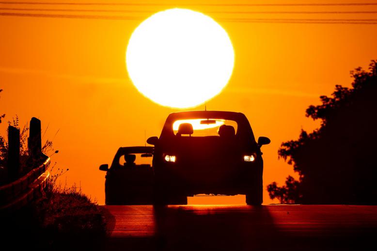 مشهد غروب شمس وراء سيارة