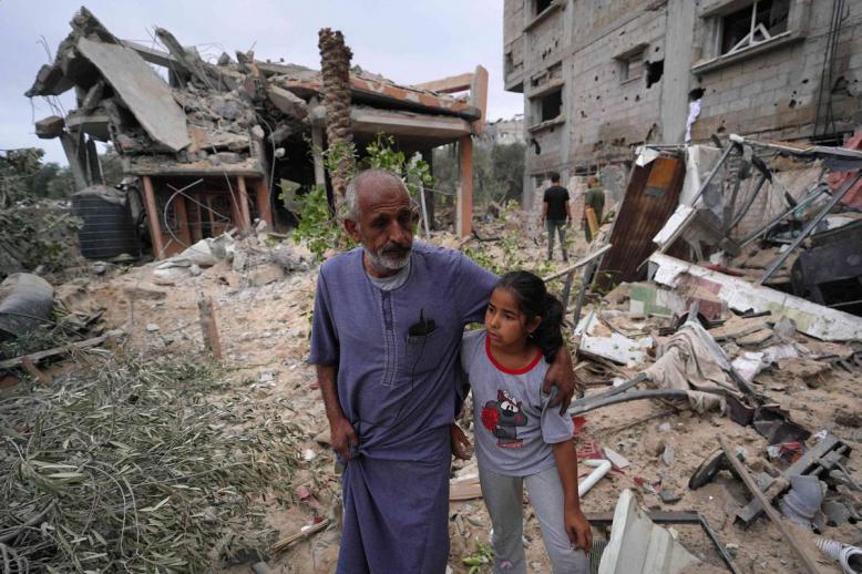 فلسطينيون عند ركام مبان دمرها القصف في غزة