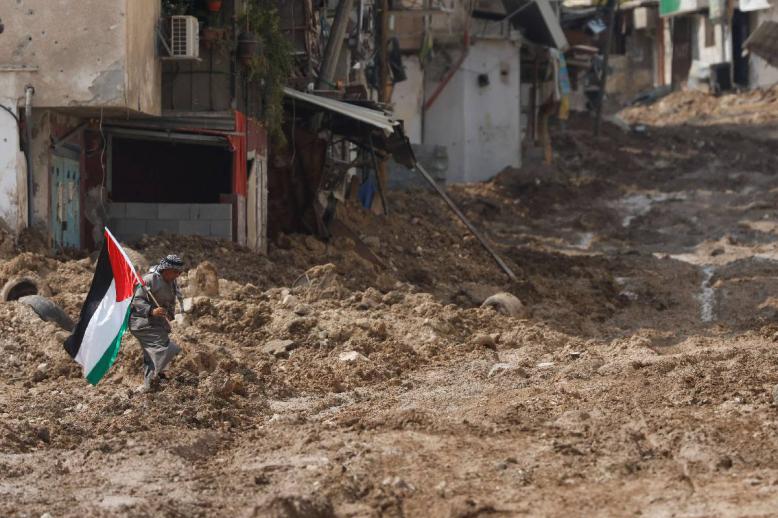 فلسطيني يرفع علما في شارع مدمر في طولكرم