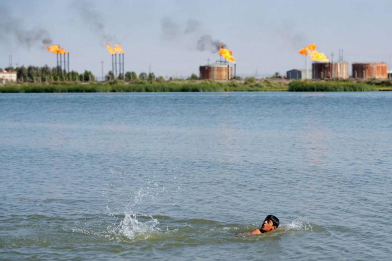 طفل عراقي يسبح بالقرب من منشآت نفطية في حقول نهر بن عمر بالبصرة