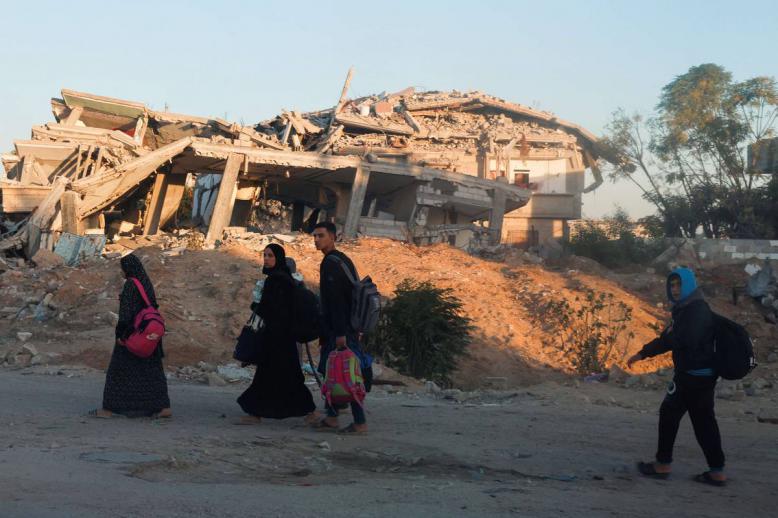 أسرة فلسطينية أمام مبان مدمرة في خان يونس بغزة