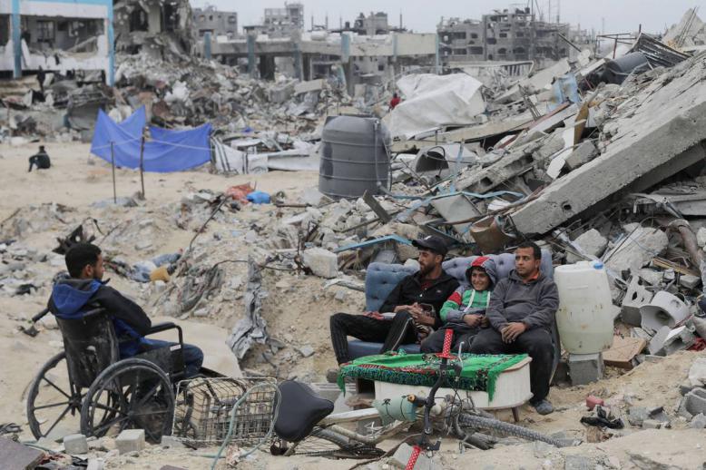 فلسطينيون يجلسون أمام انقاض منازلهم في غزة