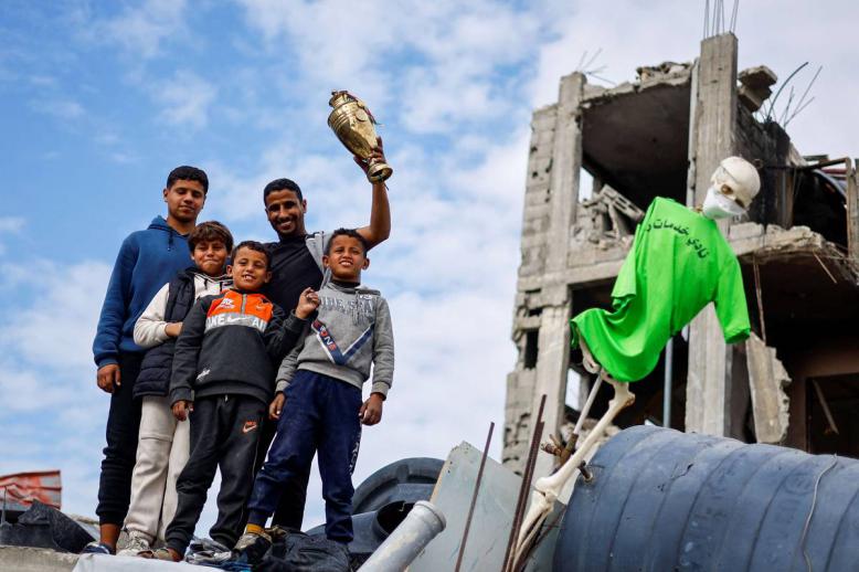 لاعب المنتخب الفلسطيني أحمد اللولحي يستخلص كأس بطولة سابقة من منزله المدمر