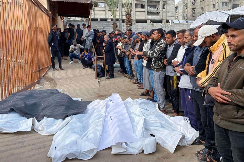 Palestinians pray by the bodies of casualties of Israeli strikes, outside the Nasser hospital in Khan Yunis