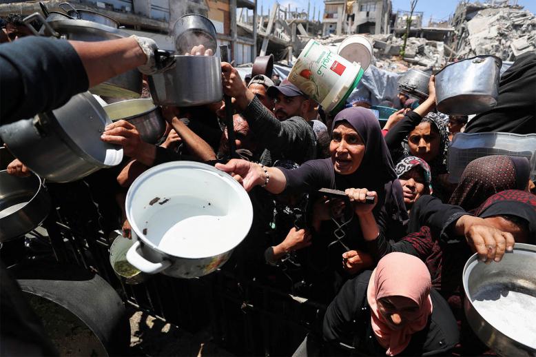 Palestinians wait to receive food cooked by a charity kitchen, in Beit Lahia