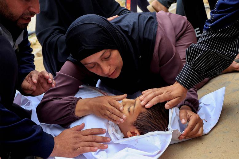 Mourners react as they look at the body of a Palestinian boy killed in an Israeli strike