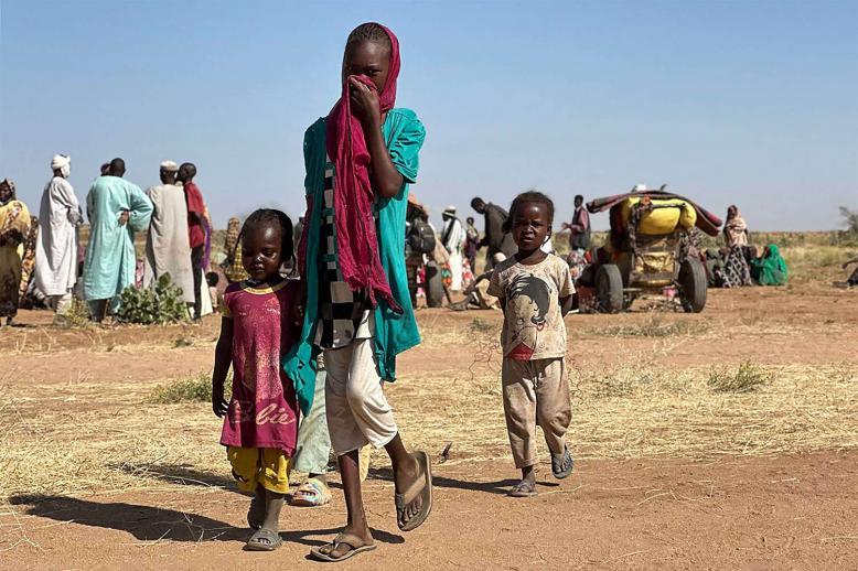 A displaced Sudanese woman, accompanied by children, walks at a camp near the town of Tawila in North Darfur