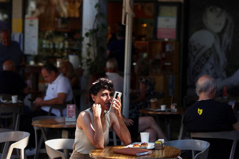 Israelis sit at a cafe, after US President Trump announced a ceasefire between Israel and Iran, in Haifa