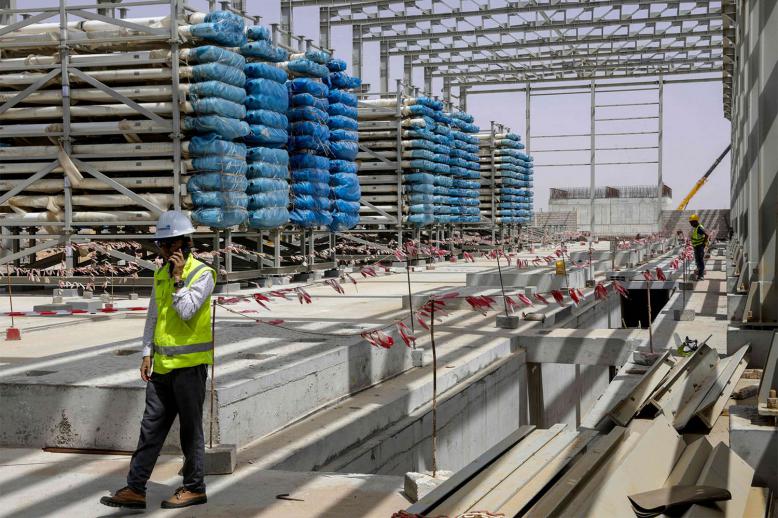 Workers stand near next to heavy equipment during the construction of a desalination plant in Dakhla