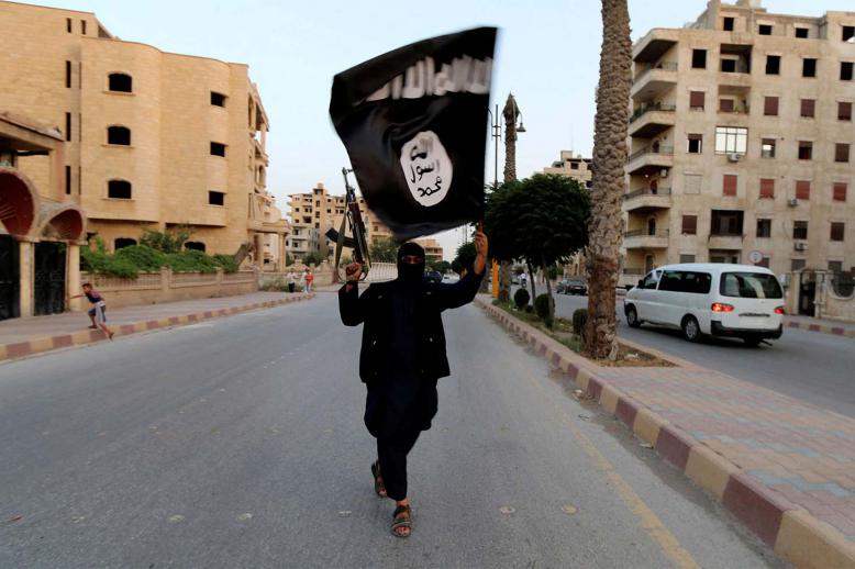 A member loyal to the Islamic State in Iraq and the Levant (ISIL) waves an ISIL flag in Raqqa, Syria June 29, 2014