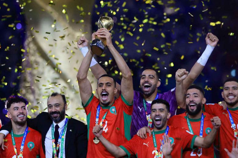Morocco’s Soufiane Bouftini celebrates on the podium with the FIFA Arab Cup trophy along with teammates and coach Tarik Sektioui et Lusail Stadium in Qatar, December 18, 2025. 