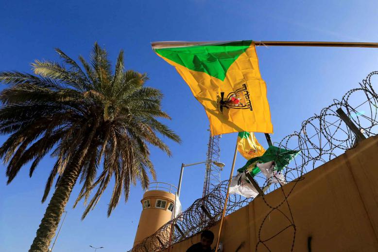 A member of Hashd al-Shaabi (paramilitary forces) holds a flag of Kataib Hezbollah militia group in Baghdad.