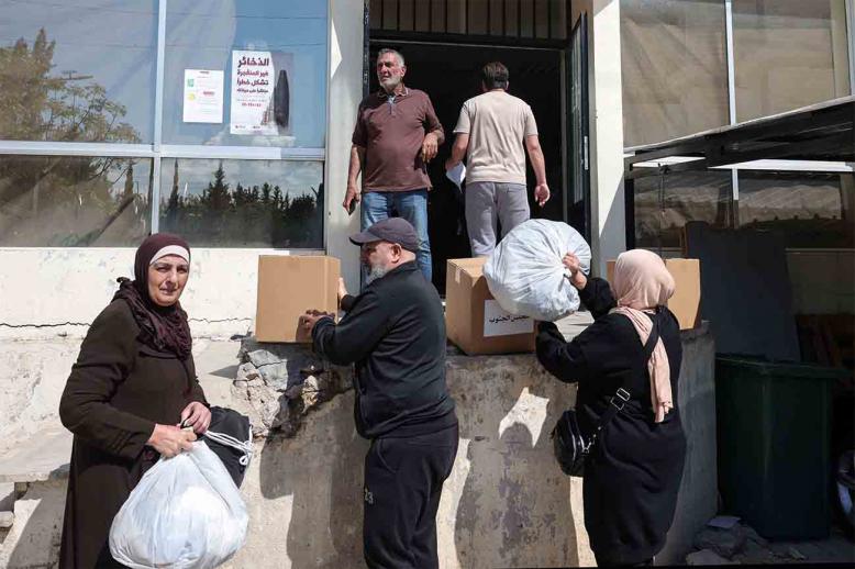 People receive food packages and other aid at the municipality center in Tyre