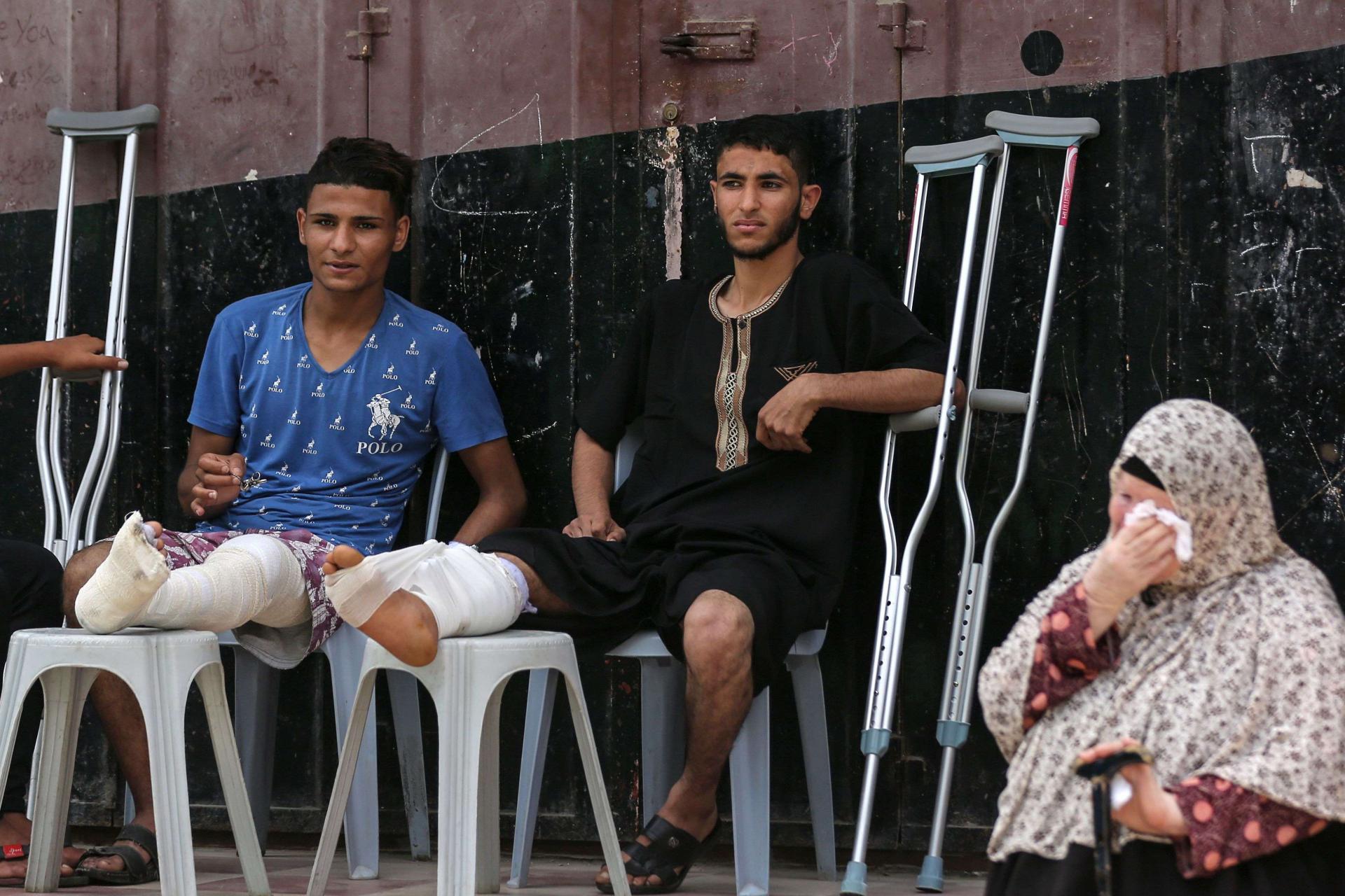 فلسطينيون اصيبوا في ارجلهم في المواجهات الأخيرة مع الاسرائيليين يحضرون مأتما لفلسطيني قتل في المواجهات
