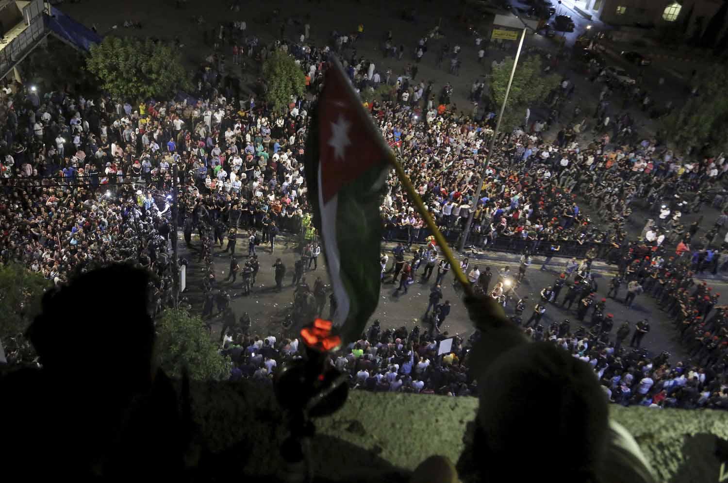 أردنيون يلوحون بعلم بلادهم من فوق بالكونة تطل على جمع متظاهر