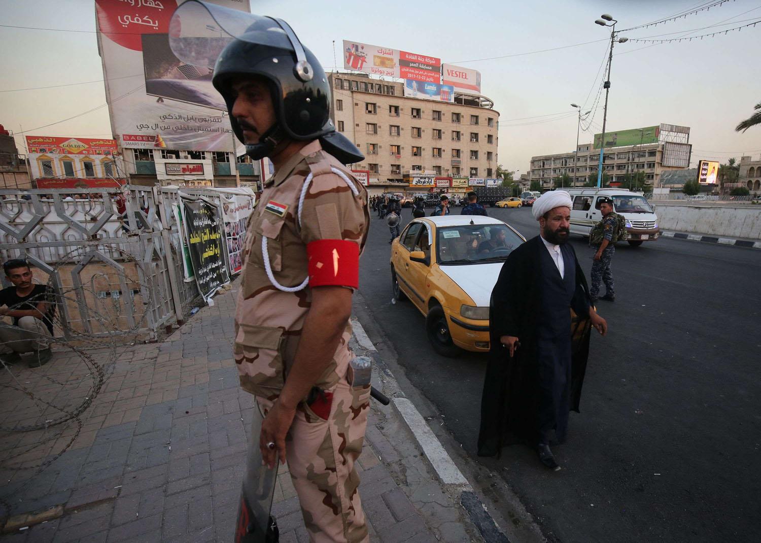 رجل دين يمر بالقرب من تظاهرة عراقية وسط بغداد