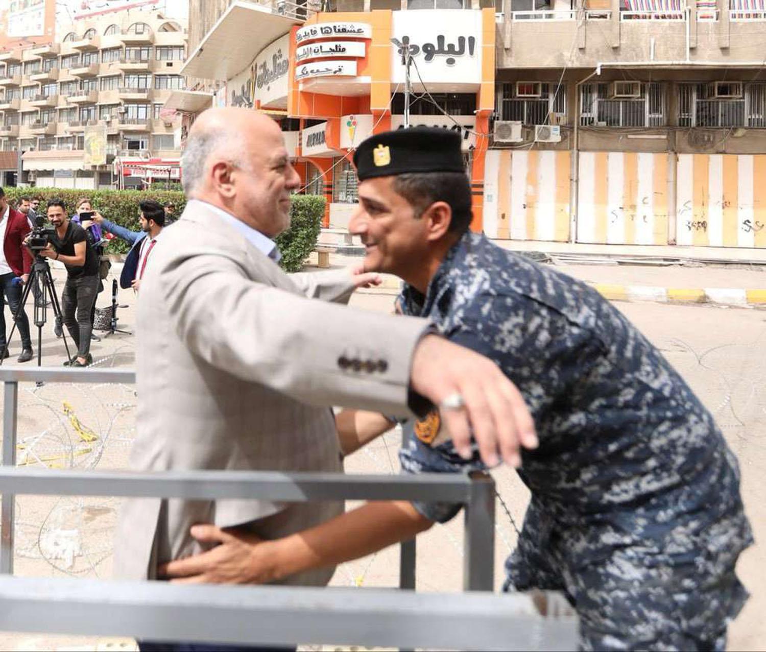 شرطي يفتش رئيس الوزراء العراقي أمام مركز انتخابي