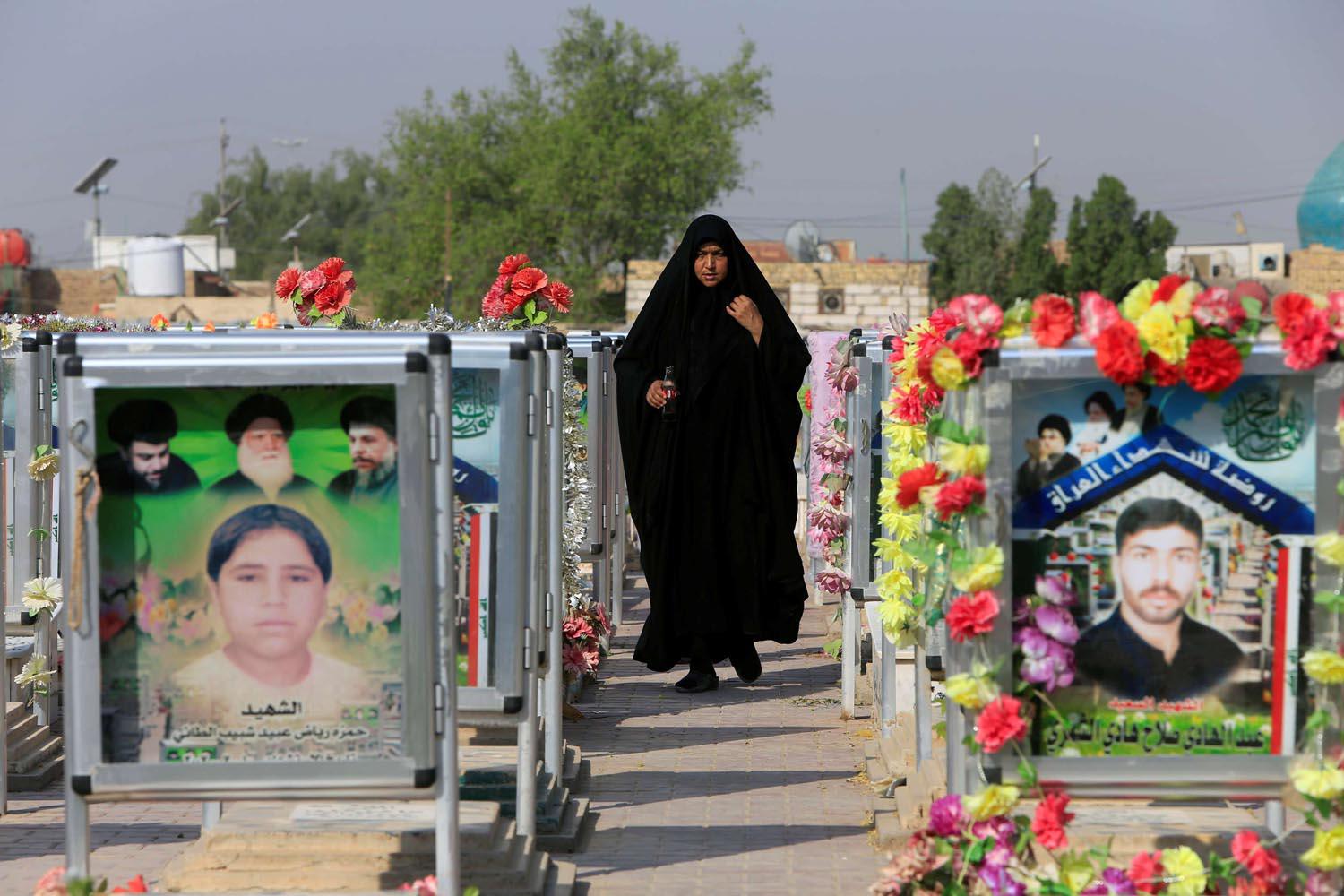 عراقية تمر بين القبور في مقبرة وادي السلام في النجف
