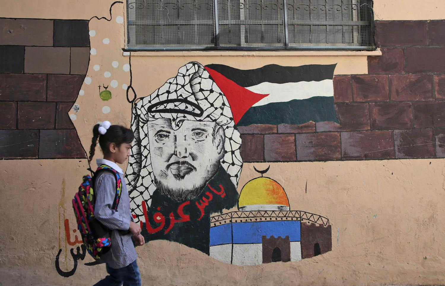 طفل فلسطيني يمر بجانب جدارية لياسر عرفات في نابلس  