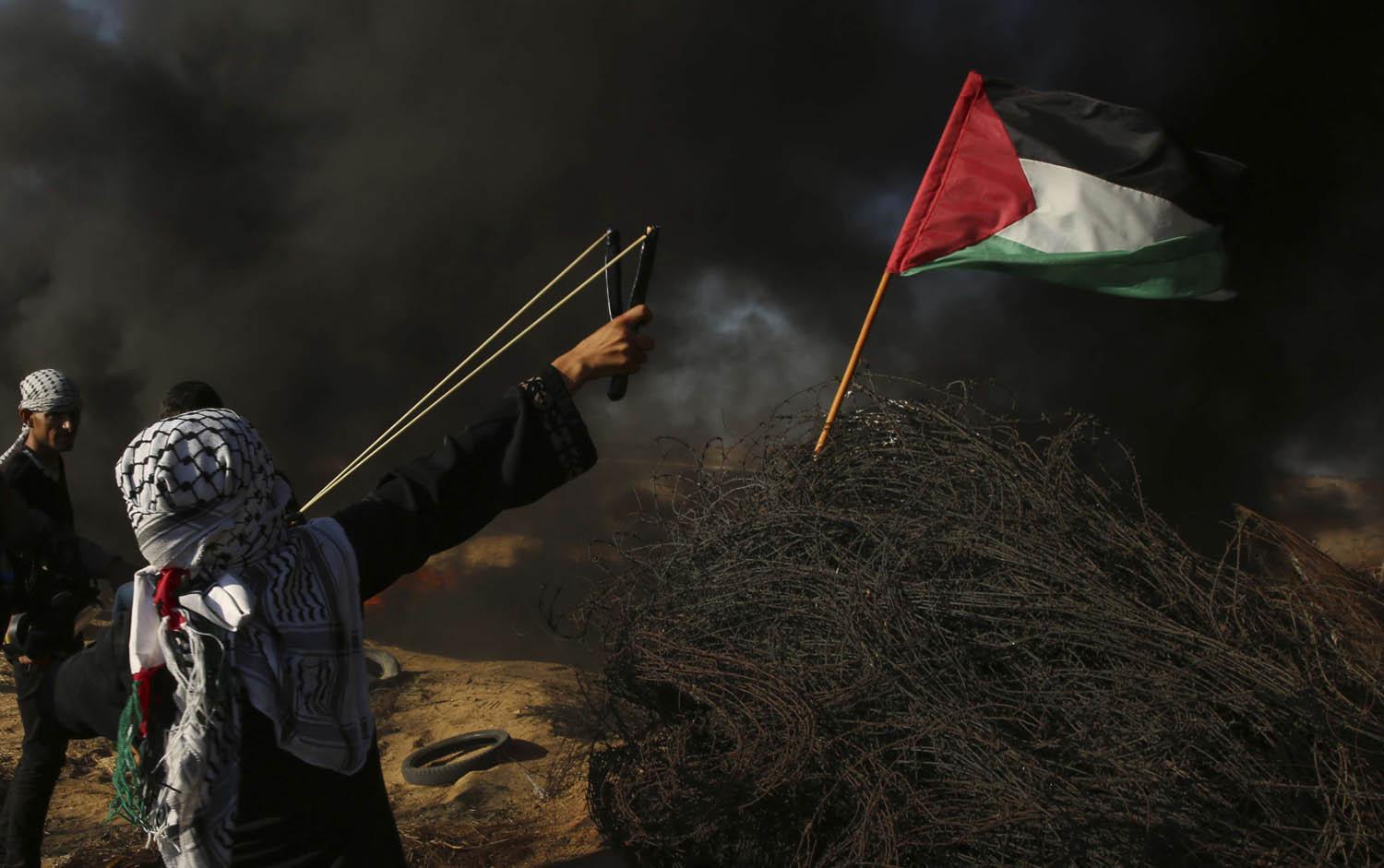 طفل فلسطيني يرمي حجارة بمصيادته على الاسرائيليين