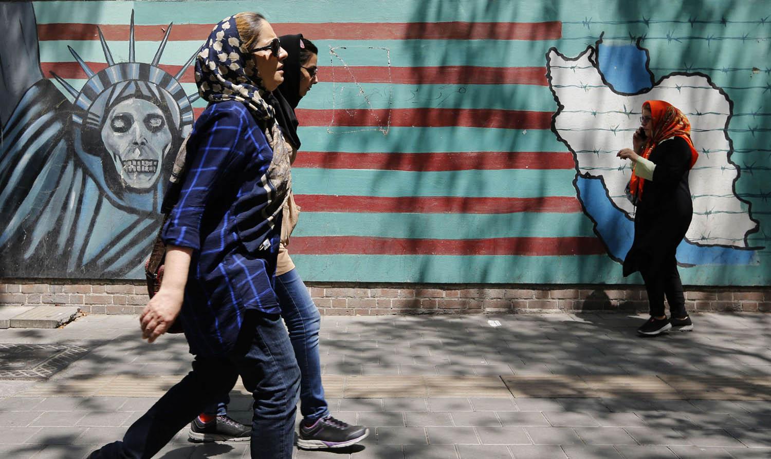 فتيات يمررن بجانب حائط عليه رسوم مناهضة للولايات المتحدة