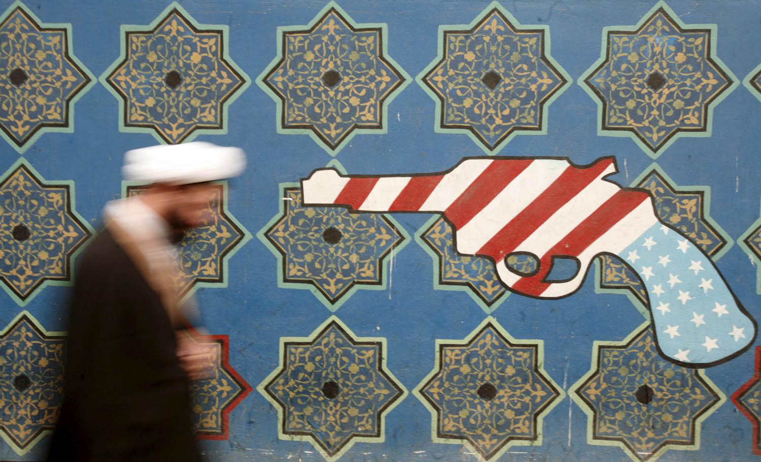 شيخ إيراني يمر بالقرب من جدارية في طهران