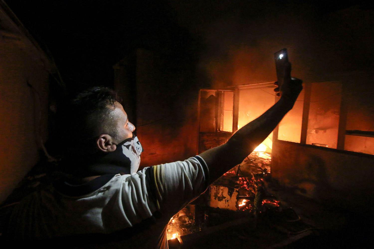 عراقي يأخذ صورة سيلفي وسط حرائق القنصلية الإيرانية في البصرة