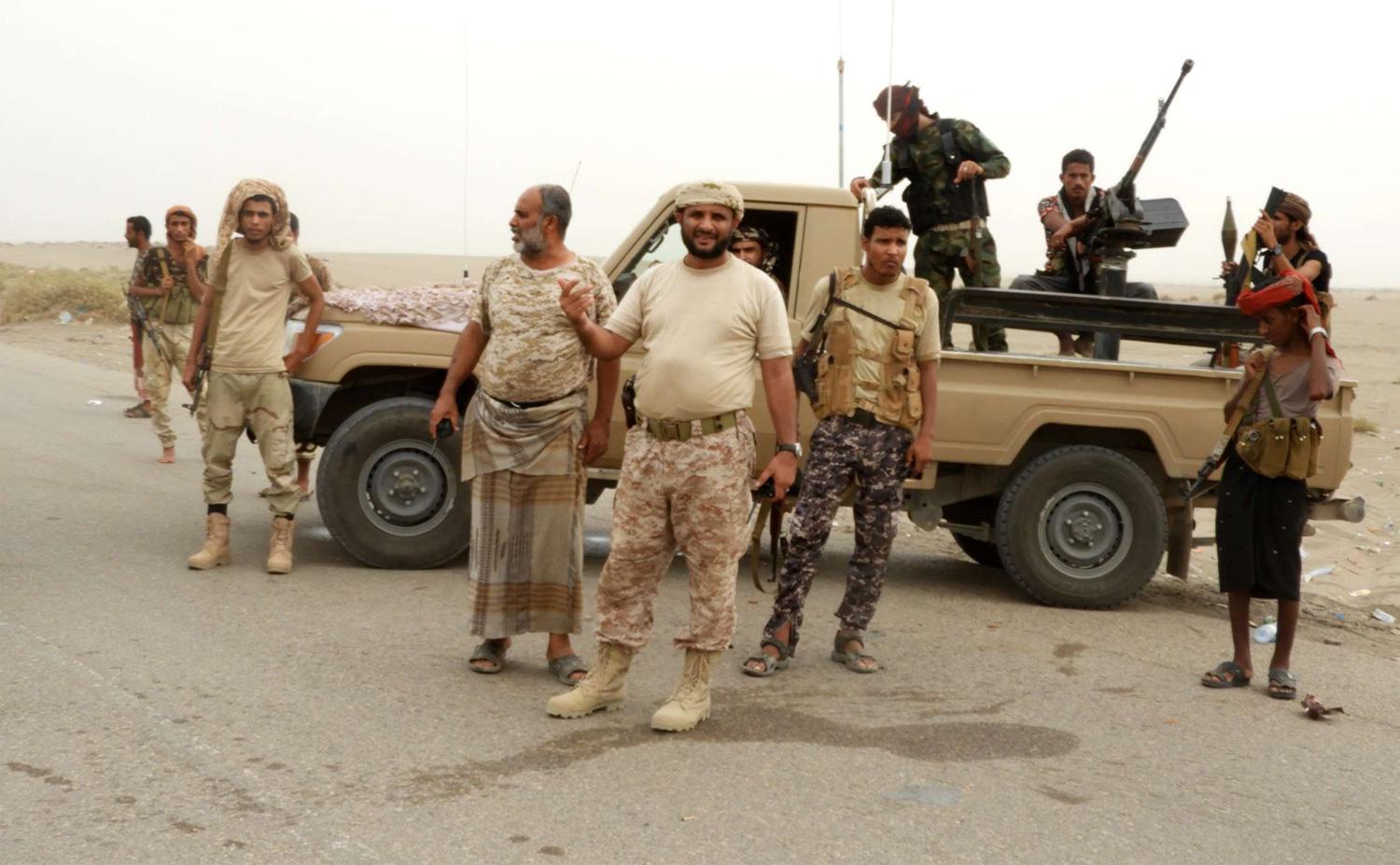 Yemeni pro-government forces stand next to a pickup truck carrying anti-aircraft guns outside Hodeidah