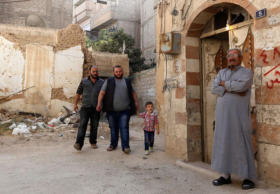 أحمد الكردي أمام منزله رفقة ابنيه وحفيده