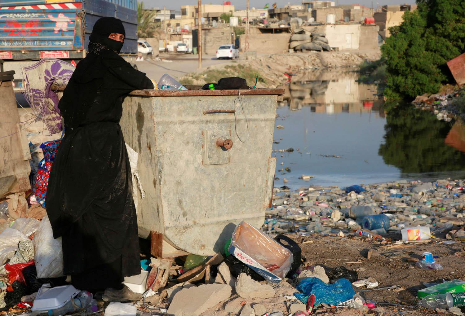 عراقية تبحث في الزبالة عن مواد يمكن بيعها في البصرة
