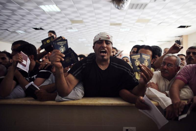  Palestnian man, who is hoping to cross into Egypt, shouts as he holds his passport and other family members’ passports at the Rafah border crossing