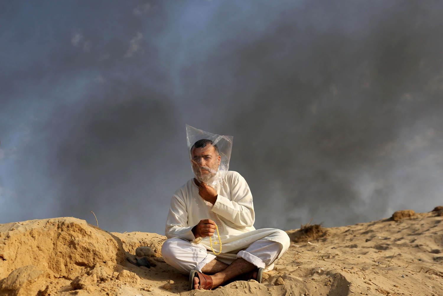 فلسطيني في بيت لاهيا يضع كيسا بلاستيكيا على رأسه في مواجهة الدخان والغازات المسيلة للدموع