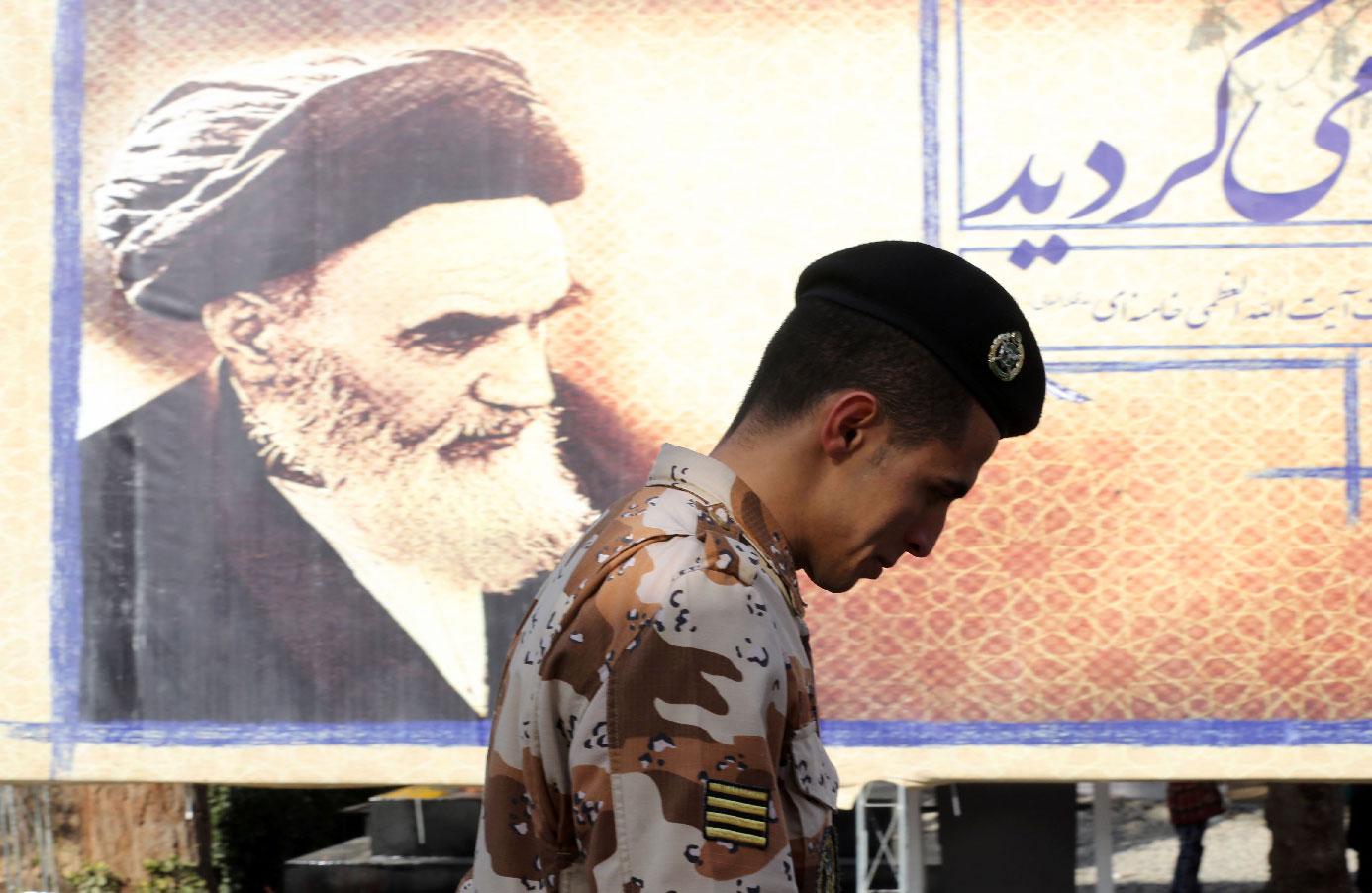 An Iranian soldier walks past a giant board displaying a portrait of the late founder of the Islamic Revolution Ayatollah Ruhollah Khomeini.