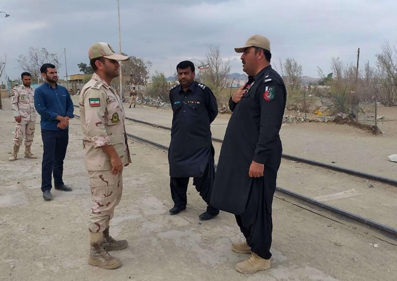 A Pakistani border security official (R) and an Iranian border official meet at Zero Point in the Pakistan-Iran border town of Taftan, on October 16
