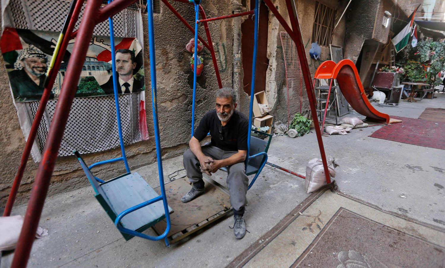 فلسطيني يجلس على أرجوحة في مخيم اليرموك بدمشق