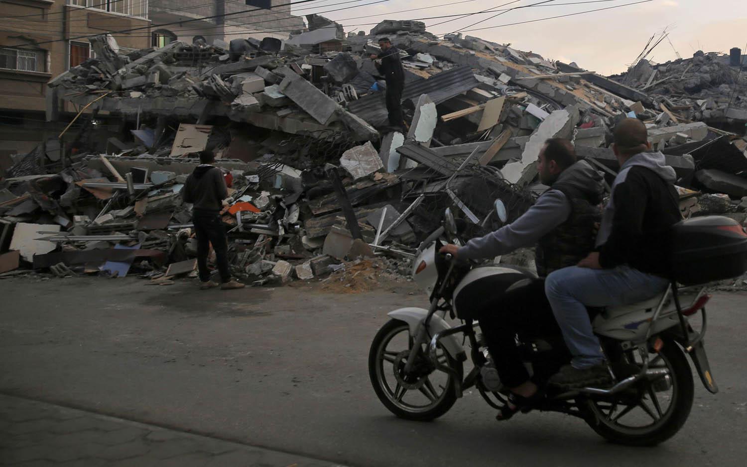 فلسطينيون يمرون بالقرب من مبنى دمرته غارة إسرائيلية في غزة